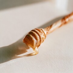 Fototapeta premium Hand-carved wooden honey dipper with glistening honey drip on cream backdrop
