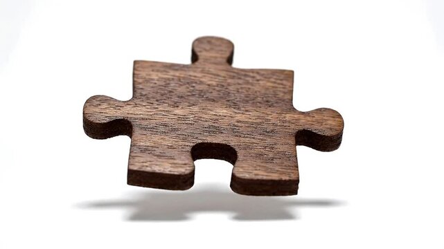 Wooden jigsaw puzzle piece rotating against a white background