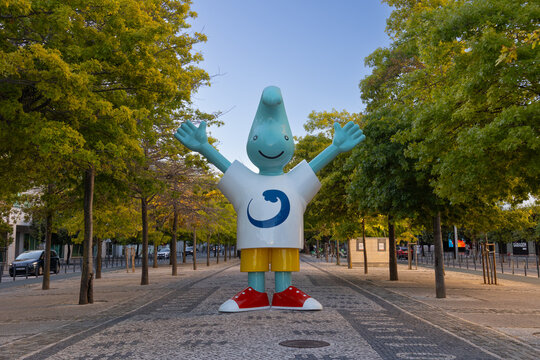 20260717 Lisboa, Portugal - Gil, the friendly mascot created for Expo 98, stands with open arms along a tree-lined pedestrian avenue in Parque das Na&ccedil;&otilde;es. The iconic public sculpture is a recognizable