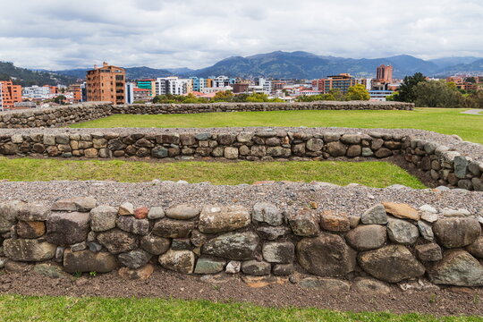 The stone ruins of the ancient Inca city of Tomebamba in the Pumapungo Archaeological Park, located in Cuenca. A picturesque view of the modern city surrounded by green hills and mountains. Ecuador.