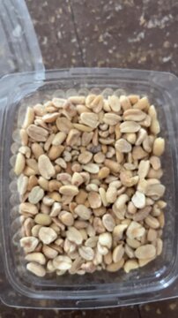 Hand picking up peanuts from bowl of roasted nuts