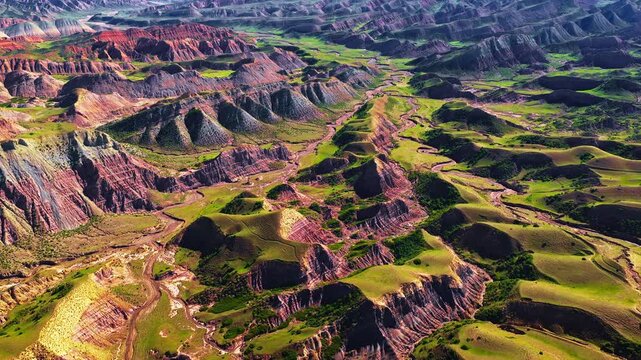 Aerial view of dramatic multi-colored mountain ranges and green valleys in Xinjiang, China.