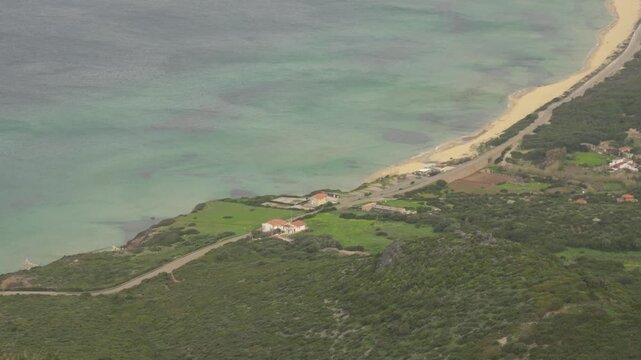 Coastal Road Winding Along Sandy Beach And Turquoise Waters Of Portixeddu Bay Near San Nicolo In Sardinia, Italy. aerial shot