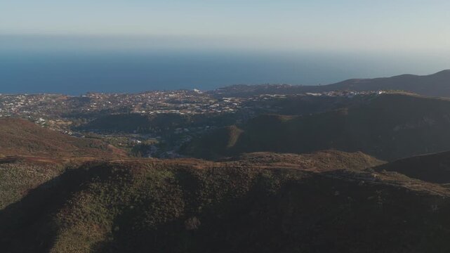 Epic sunset aerial along a scenic hiking trail in Topanga State Park, a premiere nature destination in the Santa Monica mountains with the Los Angeles coastline and Pacific Ocean in the distance.