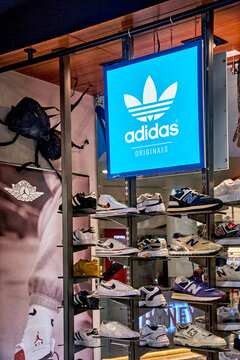 Ambato, Ecuador - October 28, 2025: Adidas Originals display featuring various sneaker models on shelves inside a retail shop with a blue illuminated sign