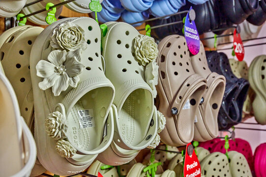 Ambato, Ecuador - November 07, 2025: Crocs shoe footwear displayed on a rack with decorative floral jibbitz charms embellishments in a retail store setting, various colors and styles visible