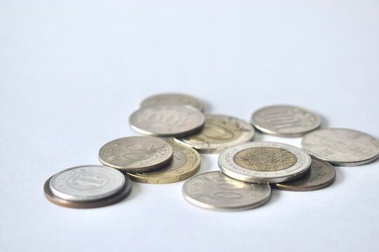 A scattered collection of various international metal coins from different countries, featuring different sizes and colors, laid out on a plain white surface.
