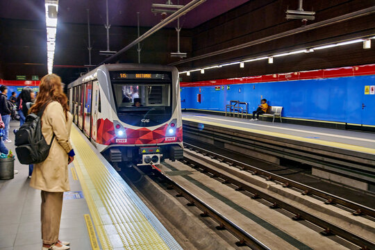 Quito, Ecuador - May 12, 2026: Subway train arriving at platform with passengers waiting, colorful walls and seating visible in modern underground station