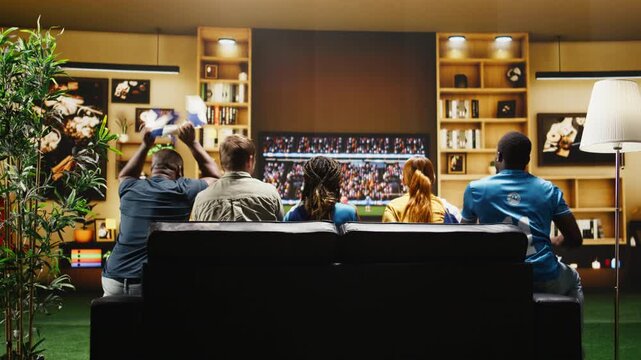 Football fans react frantically to a missed chance on TV from the sofa while supporters stay agitated by referee decisions in a dramatic soccer game.