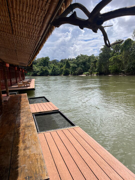 Cozy wooden deck of a floating raft cafe on the scenic River Kwai in Kanchanaburi, Thailand.