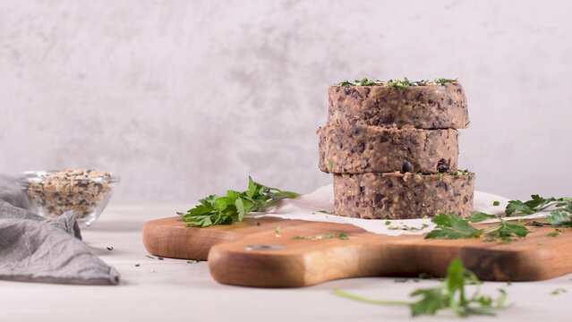 Stack of raw black bean burger patties on a wooden cutting board