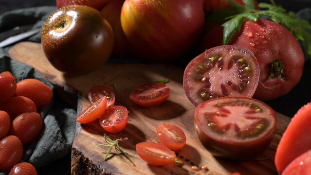 Fresh organic heirloom tomatoes sliced on a rustic wooden cutting board