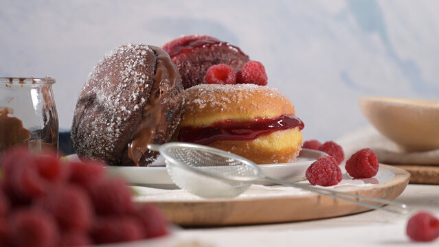 Chocolate and raspberry filled sugar donuts on a wooden board