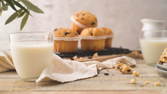 Glass of milk with chocolate chip muffins on a rustic wooden table