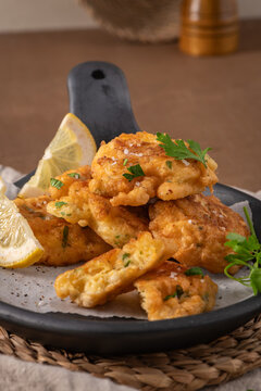 Golden crispy corn fritters served in a rustic black skillet with lemon wedges