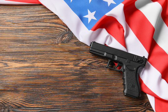 Black pistol on an american flag and dark wooden background, gun control and second amendment