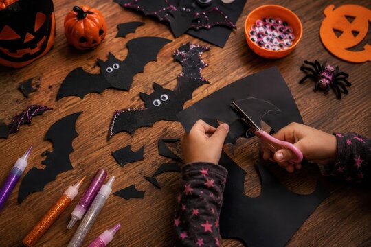 Halloween Kids Craft Activity Cutting Black Paper Bats With Scissors at Wooden Table