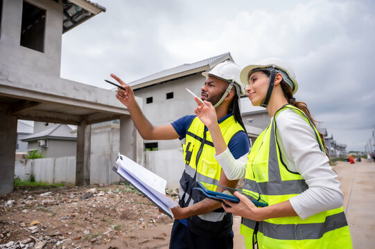 Civil construction site managers holding clipboard at residential construction site, inspection unfinished residential building during daytime, scene of house inspection and real estate development.