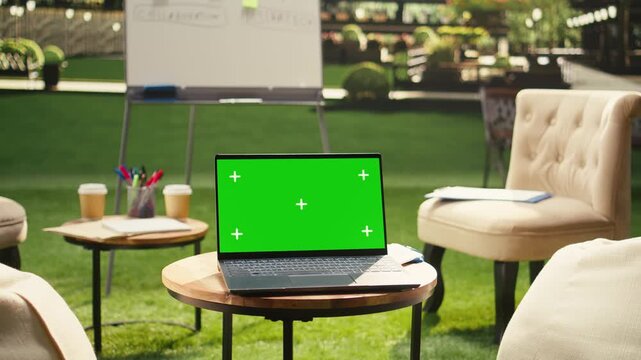 Laptop green screen on table in clean empty rooftop office terrace, editable screen replacement and chroma key mockup, outdoor business environment, urban office, for screen replacement.
