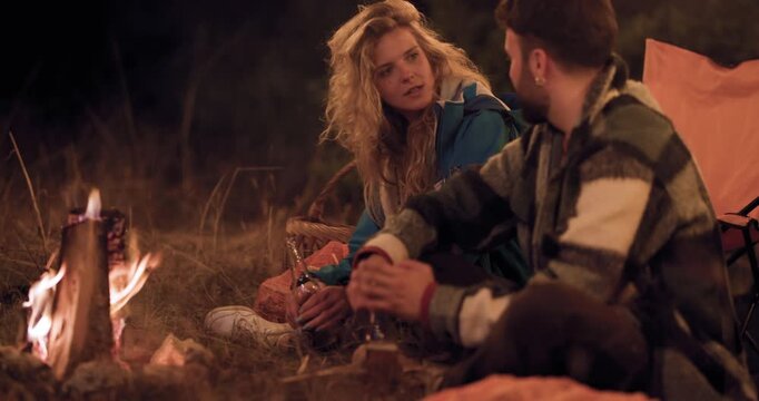 Enjoying a night by the campfire with friends under the stars at a campsite while sharing stories and laughter in the forest
