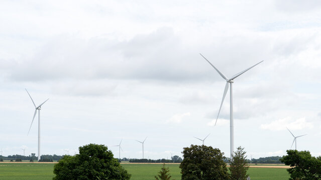 A modern wind turbine towers over rural land beneath a dramatic cloudy sky, symbolizing renewable energy, clean power, and sustainable electricity.