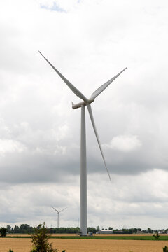 A modern wind turbine towers over rural land beneath a dramatic cloudy sky, symbolizing renewable energy, clean power, and sustainable electricity.