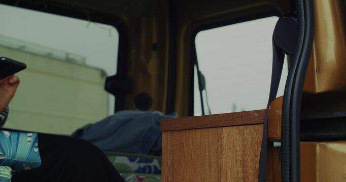 A closeup shot of a persons hand holding a smartphone inside a cozy camper van, perfect for themes of remote work, travel, and digital nomad lifestyle.