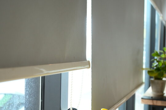 bright and minimalist interior scene featuring roller blinds covering large window