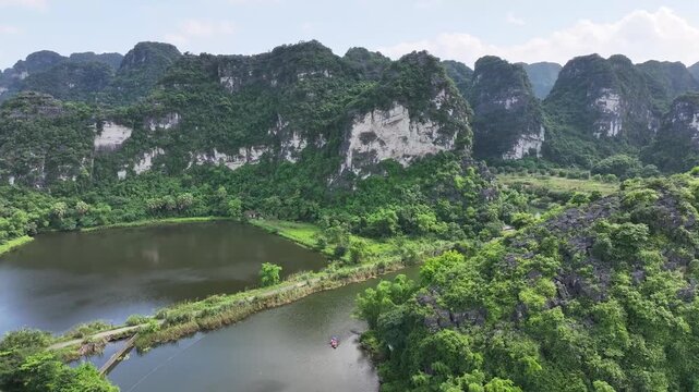 Cinematic drone footage showcasing the lush tropical landscape, towering cliffs, and scenic river canals of the famous Tam Coc region, Vietnam.