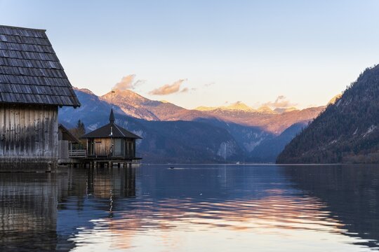 Lake Grundlsee in autumn at sunset. Boathouses on the left, mountains in the background. Blue sky, good weather. Grundlsee, Styria and Styrian Salzkammergut, Upper Austria, Austria