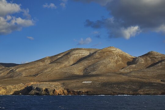 View of a hilly coastal landscape with clear sky and scattered clouds, Kassos Island, neighbouring island of Karpathos, Dodecanese, Greek Islands, Greece