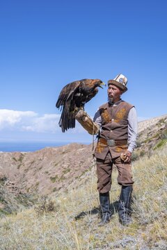 Traditional Kyrgyz eagle hunter with eagle in the mountains, near Kysyl-Suu, Kyrgyzstan