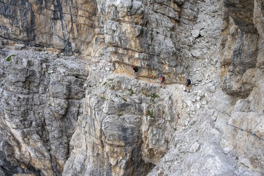 Three hikers on the Via Ferrate Benini via ferrata on a cliff, Brenta Mountains, Parco Naturale Brenta-Adamello, Trentino, Italy