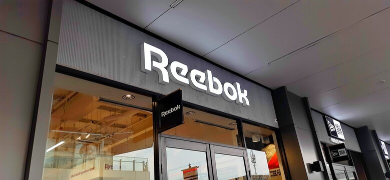 Karawang, West Java, Indonesia - May 29 2025. Reebok Storefront With Illuminated Logo and Entrance in Summarecon Villaggio Outlets