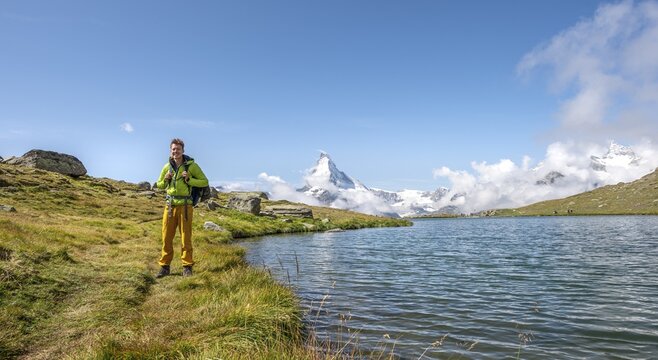 Hiker at Lake Stellisee, 5 lakes Hiking trail, snow-covered Matterhorn at the back, Valais, Switzerland