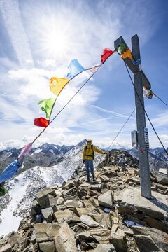 Mountaineers at the summit of B&ouml;ses Weibl with summit cross and colourful prayer flags, view of picturesque mountain landscape with snow-covered peaks, Wiener H&ouml;henweg, Schobergruppe, Hohe Tauern National Park, Carinthia, Austria