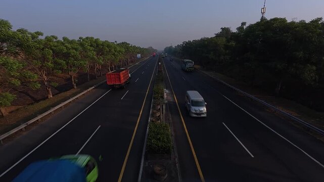 High angle shot of highway traffic at sunrise with beautiful warm and cool lighting contrast, morning commute logistics.