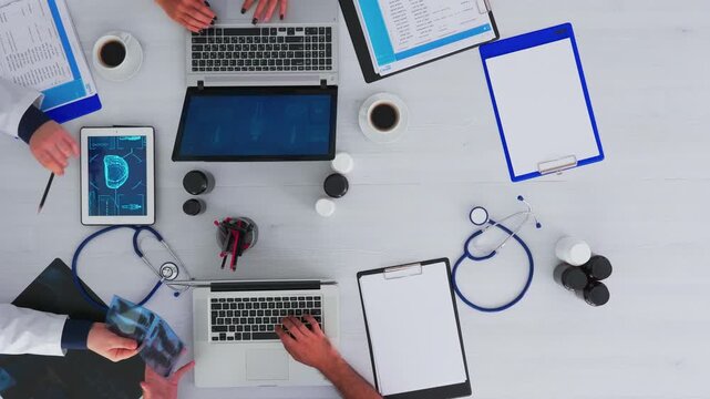 Doctor explains patient problems to a resident physician using tablet and x ray references at a clinic desk with stethoscope, devices and clinical copy space.