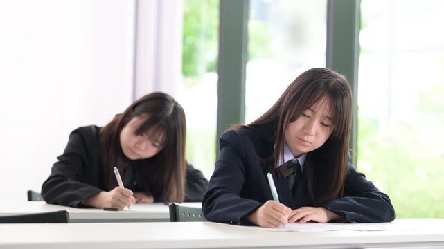 綺麗な新緑背景の教室で真剣にテストや模試へ取り組む日本人女子中学生や高校生複数　受験や定期テスト受ける動画