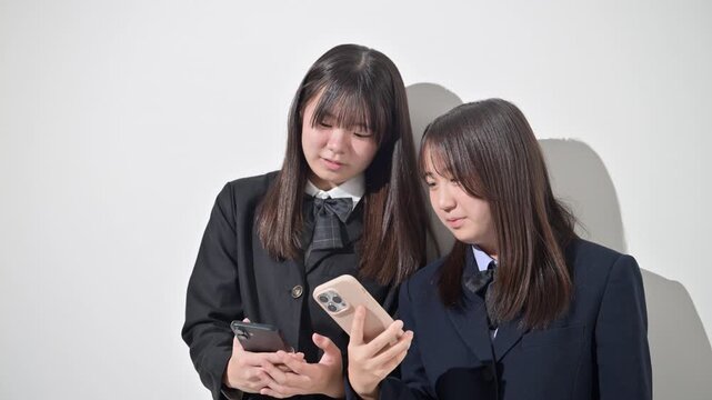スマートフォン(スマホ)を見る日本人女子中学生、女子高校生　2人で情報を共有する学校生活とコミュニケーション、スマホの安全な使い方イメージ