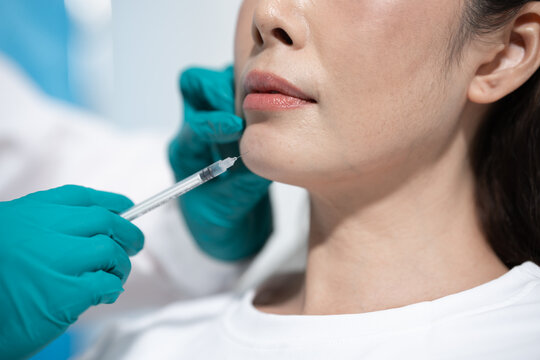 Close up of a woman getting a facial injection from a medical worker wearing gloves in a clean clinic setting