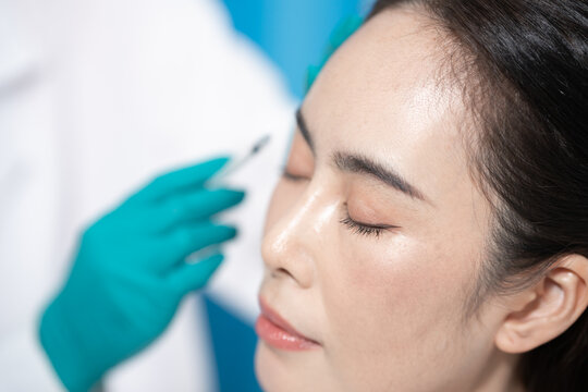 Close-up of a woman receiving a facial cosmetic injection from a gloved professional in a clinic setting.