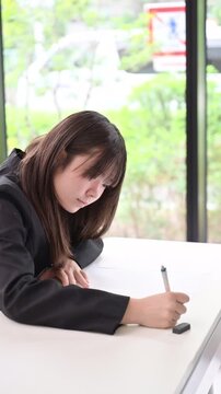 綺麗な新緑背景の教室で真剣にテストや模試へ取り組む日本人女子中学生や高校生　受験や定期テスト受ける縦動画