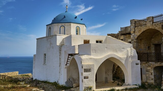 White church with blue dome by the sea, surrounded by old stone walls under a blue sky, Church of Agios Georgios, Chora, Astypalea, Dodecanese, Greek Islands, Greece