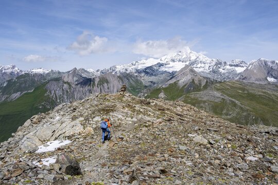Mountaineer on a hiking trail, snow-covered and glaciated summit of the Gro&szlig;glockner in the background, Wiener H&ouml;henweg, Schober Group, Hohe Tauern National Park, Carinthia, Austria