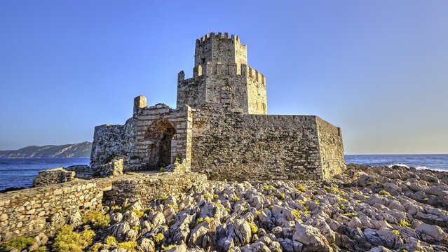 Ruins of a castle on a rocky coast with a clear sky, octagonal medieval tower. Islet of Bourtzi, sea fortress of Methoni, Peloponnese, Greece