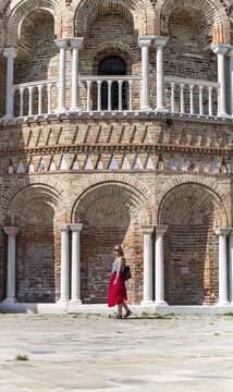 Young woman in red dress standing in front of Basilica dei Santi Maria e Donato, Murano, Murano Island, Venice, Veneto, Italy
