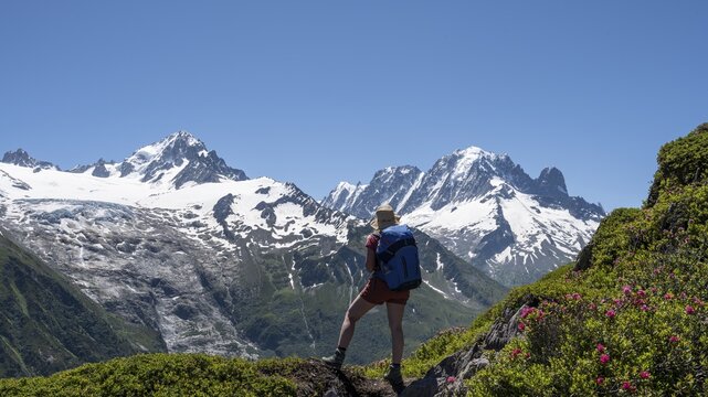 Hiker looking into the distance, mountain panorama from Aiguillette des Posettes, left summit of Aiguille Verte (right) Aiguille du Midi and Mont Blanc, Chamonix, Haute-Savoie, France