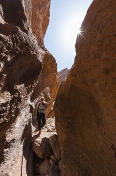 Young female hiker in a narrow sandstone canyon, solar reflex, Dades Valley, Morocco