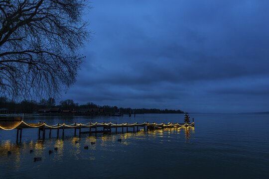 Illuminated Christmas tree at dawn, on an illuminated boat dock, Die&szlig;en am Lake Ammer, Upper Bavaria, Bavaria, Germany